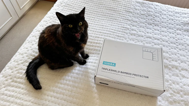 The Simba TripleShield Bamboo mattress protector in its box, alongside a cat