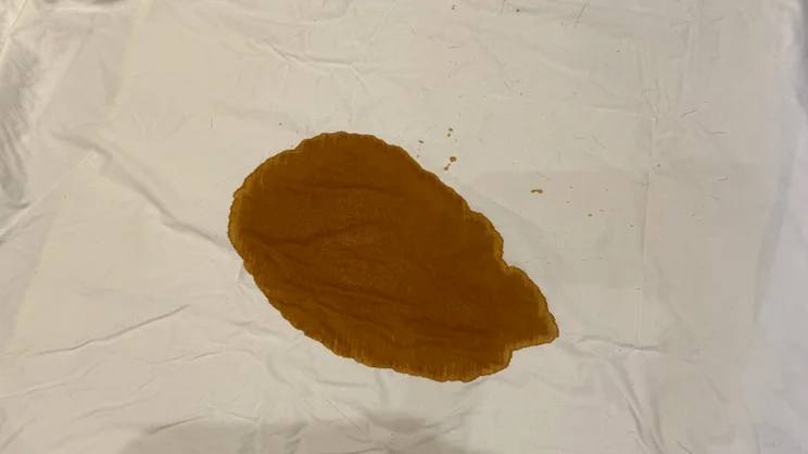 A large coffee stain on a bedsheet