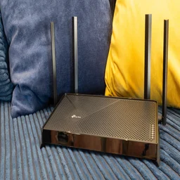 THe TP Link Archer BE3600 pictured in front of two colourful cushions