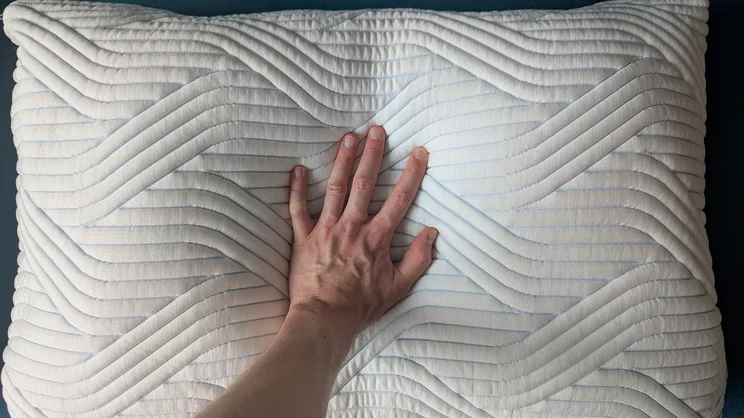 A bird's eye view of a hand, pressing down on the Tempur Cloud SmartCool pillow