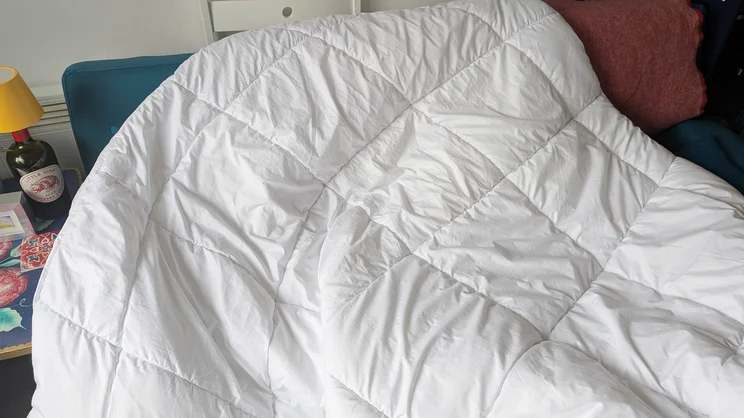 The Tempur Luxe Fibre Cooling Duvet draped over a sofa