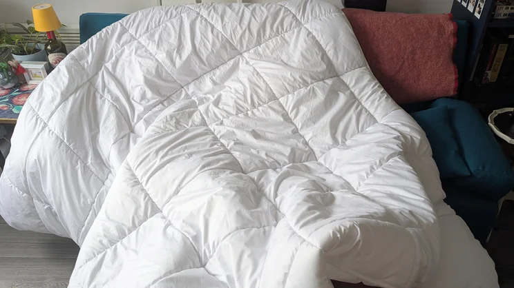 The Tempur Luxe Fibre Cooling Duvet draped over a sofa