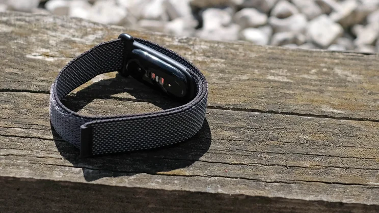 The Fitbit Air pictured on a wood surface, from the rear