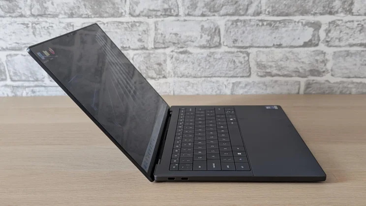 Side view of the new Dell XPS 14 laptop on a wooden table with its lid open