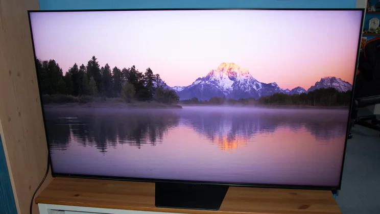 The Hisense UR8S RGB Mini LED TV displaying an image of a mountain and a lake in Filmmaker Mode