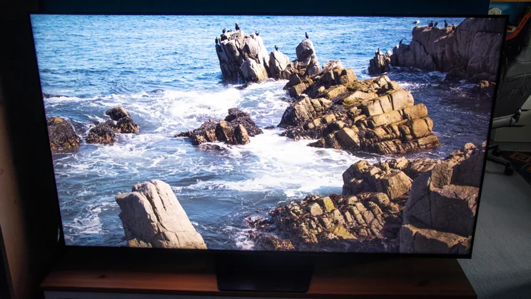 The Hisense UR8S RGB Mini LED TV displaying an image of a rocky coastline in Filmmaker Mode