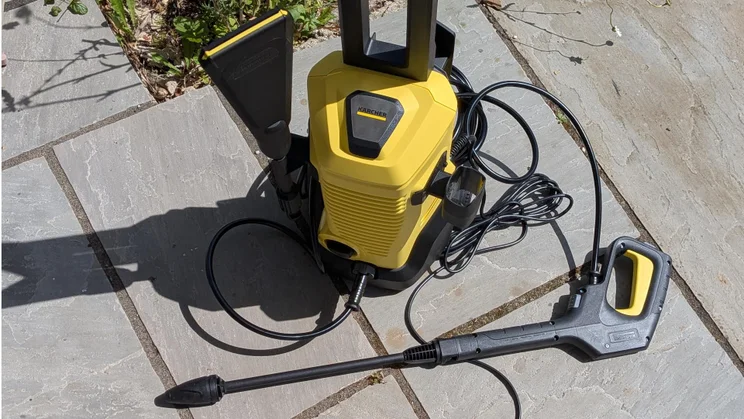 Top-down view of the K&auml;rcher K3 eco!Booster pressure washer with its Dirt Blaster lance on a patio