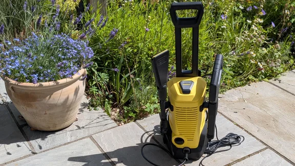 The Kärcher K3 eco!Booster pressure washer on a garden patio in front of some plants and flowers
