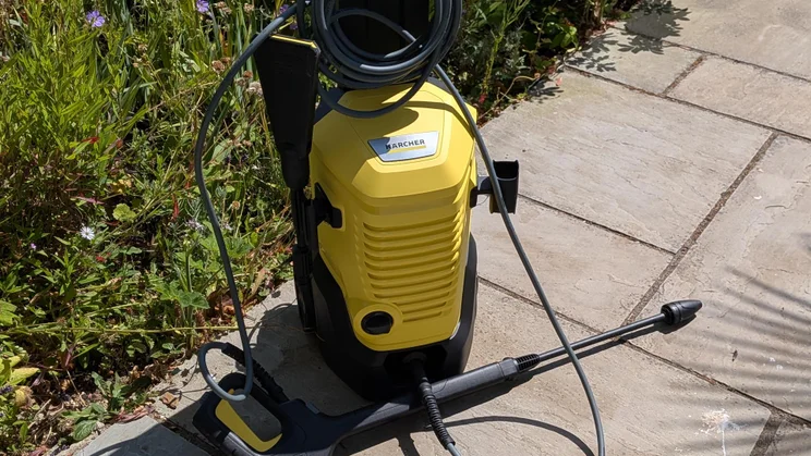 The K&auml;rcher K4 WCM Flex eco!Booster pressure washer on a patio in front of some foliage
