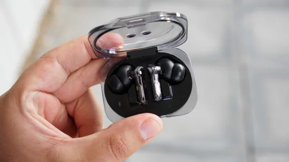 The Nothing Ear (3a) wireless earbuds being held in their charging case with the lid open being