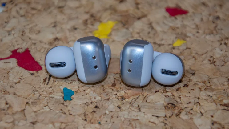 The Shokz OpenDots 2 wireless earbuds on a cork table showing their battery drums and speaker grilles