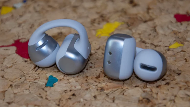 The Shokz OpenDots 2 wireless earbuds side by side on a cork table