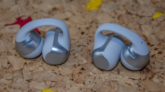 The Shokz OpenDots 2 wireless earbuds on a cork table