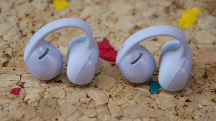 The Shokz OpenDots Air open-ear wireless earbuds next to each other on a cork table