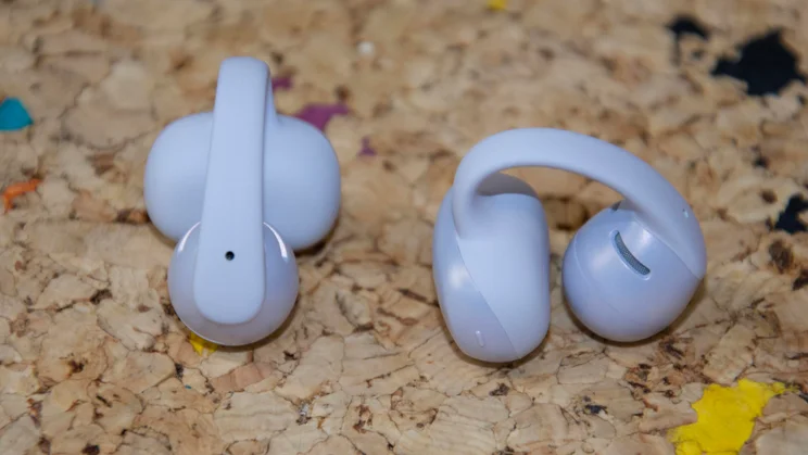 The Shokz OpenDots Air open-ear wireless earbuds side by side on a cork table