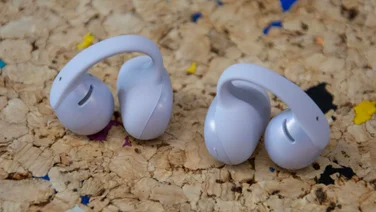 The Shokz OpenDots Air open-ear wireless earbuds on a cork table