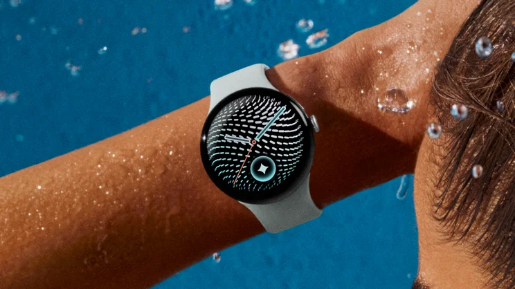 The Pixel Watch 5 in Fog, pictured on wrist, surrounded by water droplets with a blue background