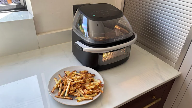 The Cuisinart Clearview 9-in-1 air fryer on a kitchen worktop, alongside a plate of cooked chips