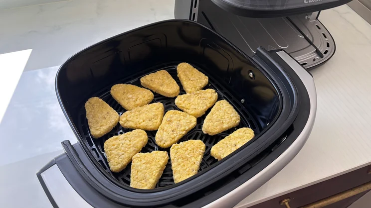 A bird's eye view of raw hash browns in the Cuisinart Clearview 9-in-1 air fryer's open drawer