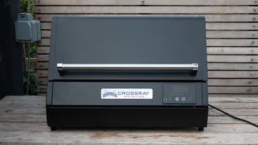 The Dimplex Crossray eXtreme BBQ, without its stand, on a wooden bench