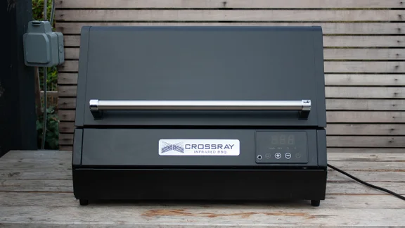 The Dimplex Crossray eXtreme BBQ, without its stand, on a wooden bench
