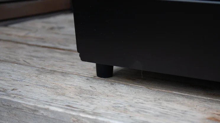 The Dimplex Crossray eXtreme BBQ on a wooden bench, without its stand. The photo shows a closeup of the unit's foot
