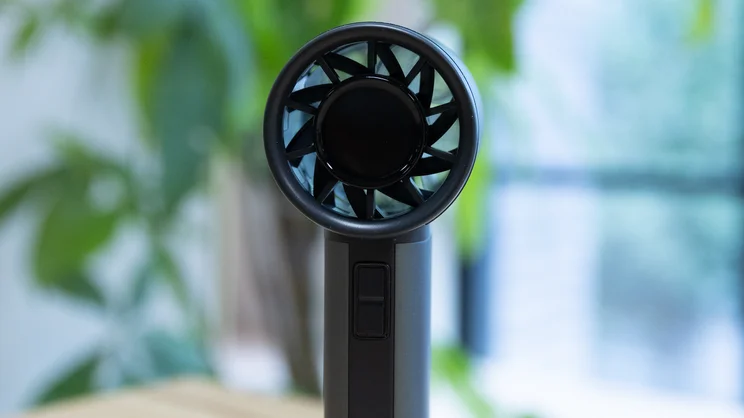 A closeup of the John Lewis High Power Handheld Fan, standing upright on an office table