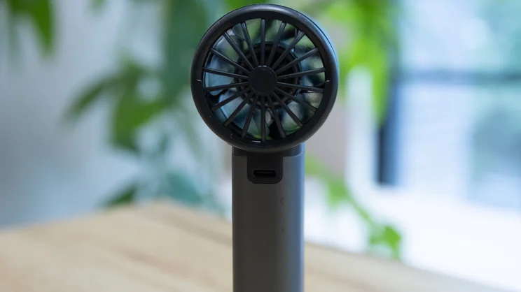 A closeup of the rear of the John Lewis High Power Handheld Fan, standing upright on an office table
