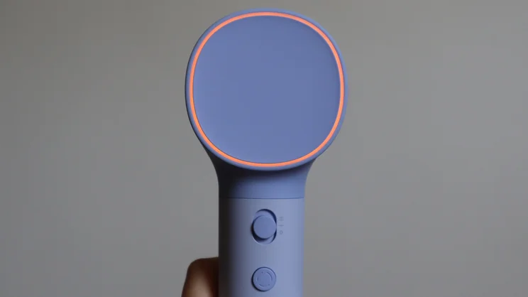 The Laifen Neo hair dryer in a hand, with its LED ring illuminated