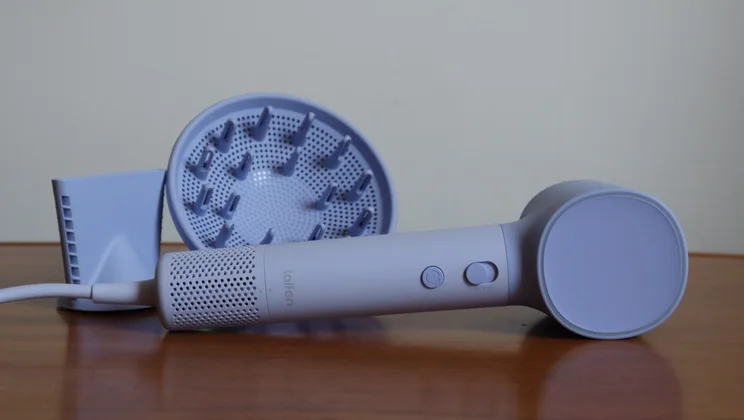 The Laifen Neo hair dryer on its side on a table, alongside its attachments