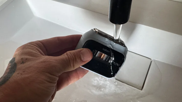 The Laifen P3 shaver being washed under a running tap in a bathroom sink