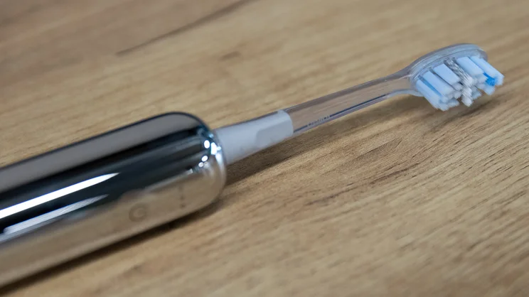 A closeup of the Laifen Wave Pro electric toothbrush, lying on its side on a table, with Plaque Removal brush head attached