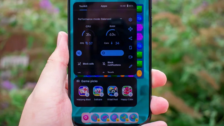 Motorola Moto G77 displaying gaming specs over a game of Candy Crush