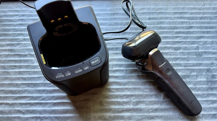 A bird's eye view of the Panasonic Series 900+ electric shaver, alongside the cleaning dock