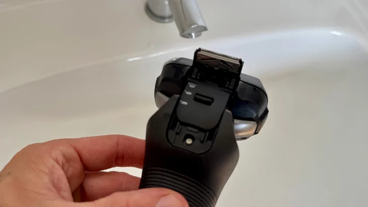 The Panasonic Series 900+ electric shaver held over a bathroom sink. Focussed on the shaver's trimmer attachment
