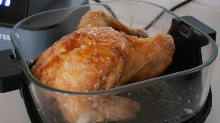 A cooked chicken inside the larger 4l dish of the Salter Crisp & Go air fryer