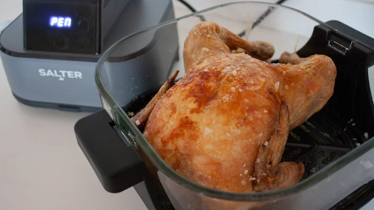 A cooked chicken inside the larger 4l dish of the Salter Crisp & Go air fryer
