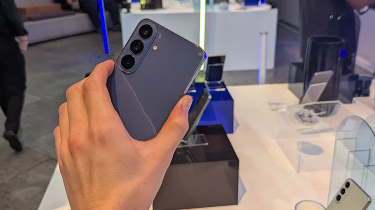 The Samsung Galaxy S26 FE smartphone in a hand, the rear of the phone facing the camera