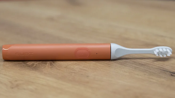The Suri Core 1.0 electric toothbrush lying on its side on an office table