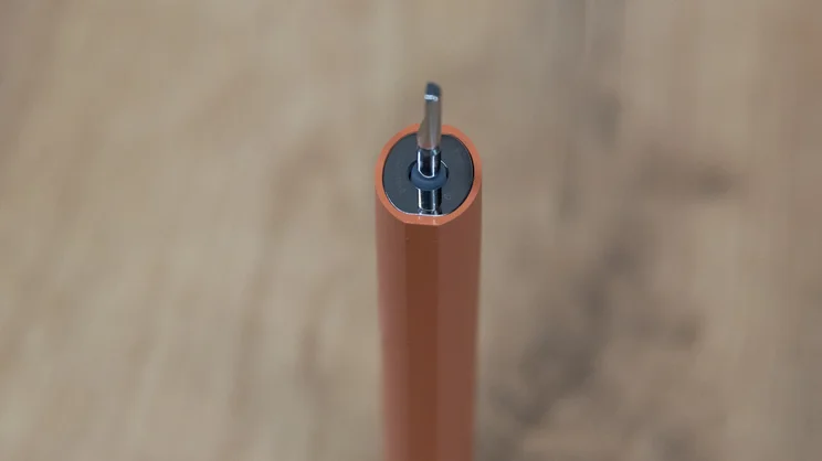 A bird's eye view of the Suri Core 1.0 electric toothbrush without its brush head, standing upright on an office table