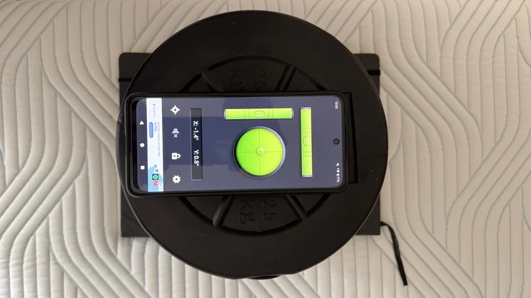 A bird's eye view of a smartphone and a stack of dumbbell plates, being used to measure edge tilt on the Tempur Pro Plus SmartCool mattress