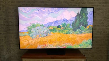 Front view of the Hisense UR9S RGB Mini LED TV displaying a digital artwork of a field and trees