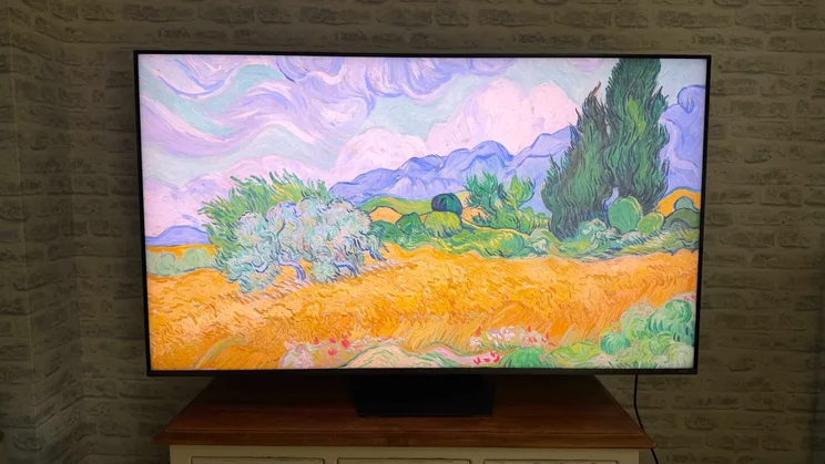 Front view of the Hisense UR9S RGB Mini LED TV displaying a digital artwork of a field and trees