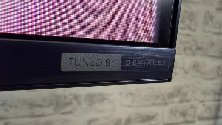 Close-up of the Tuned by Devialet logo on the bottom corner of the Hisense UR9S RGB Mini LED TV