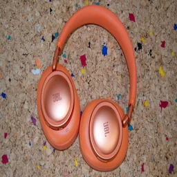 The JBL Live 780NC over-ear headphones lying flat on a cork table