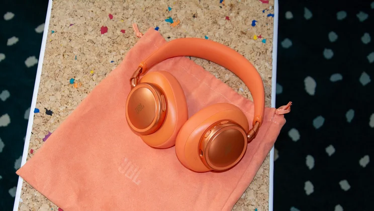 The JBL Live 780NC over-ear headphones on their fabric pouch on a cork table