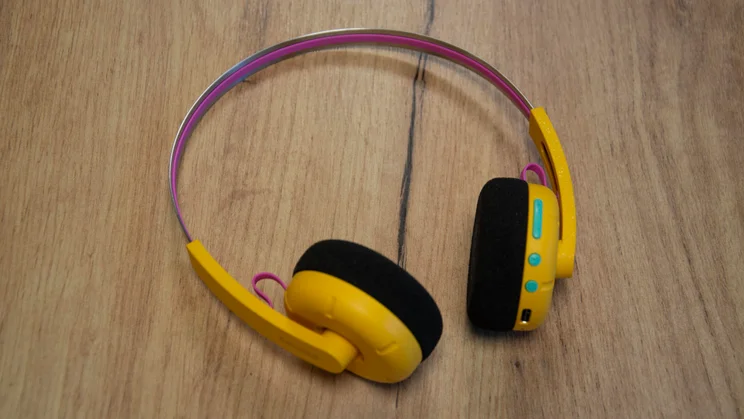 The Philips Ringo Duo on-ear headphones in yellow on a wooden table with their controls facing upwards