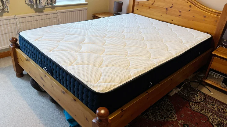 The DreamCloud Hybrid mattress on a wooden bed frame in a bedroom