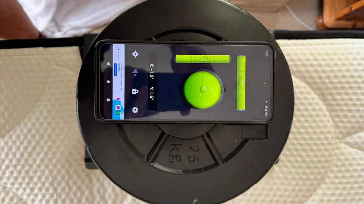 A bird's eye view of a stack of weights and smartphone at the edge of the DreamCloud Hybrid mattress, testing the tilt of the mattress