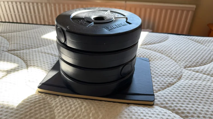 A stack of weights and a notebook being used to test sinkage on the DreamCloud Hybrid mattress